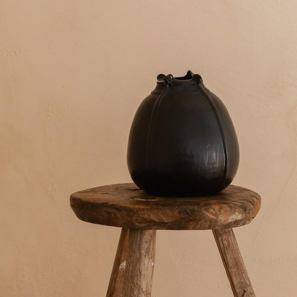 vase en céramique noir posé sur un tabouret en bois